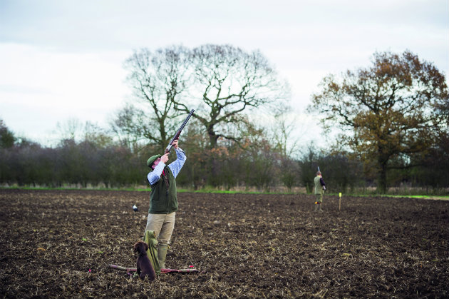 Man with shotgun in muddy field 