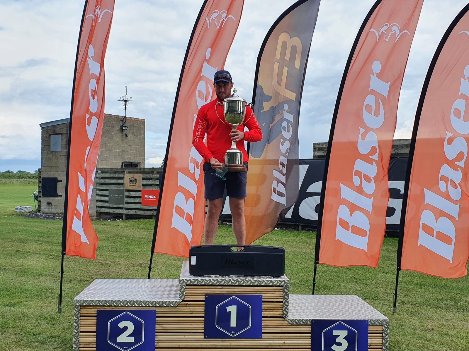 Phil Gray holding the Clay Shooting Classic trophy aloft on the winner's podium in 2022