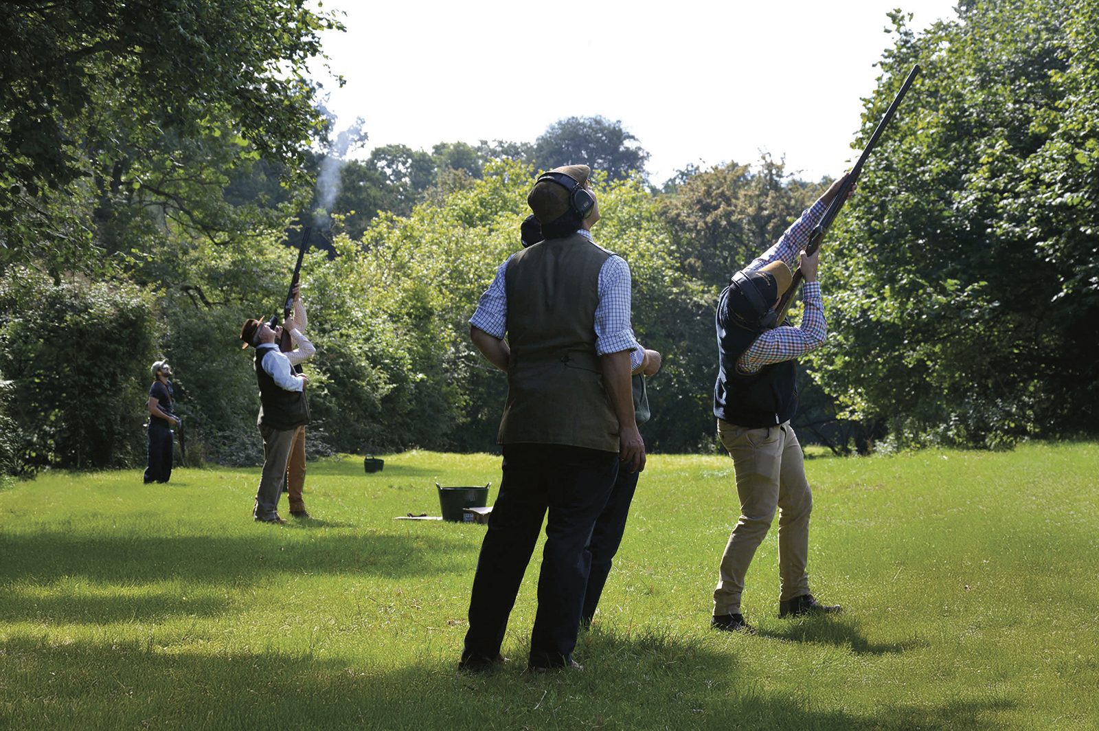 A line of Guns shooting clays in parkland on a simulated game day at Shooting School UK