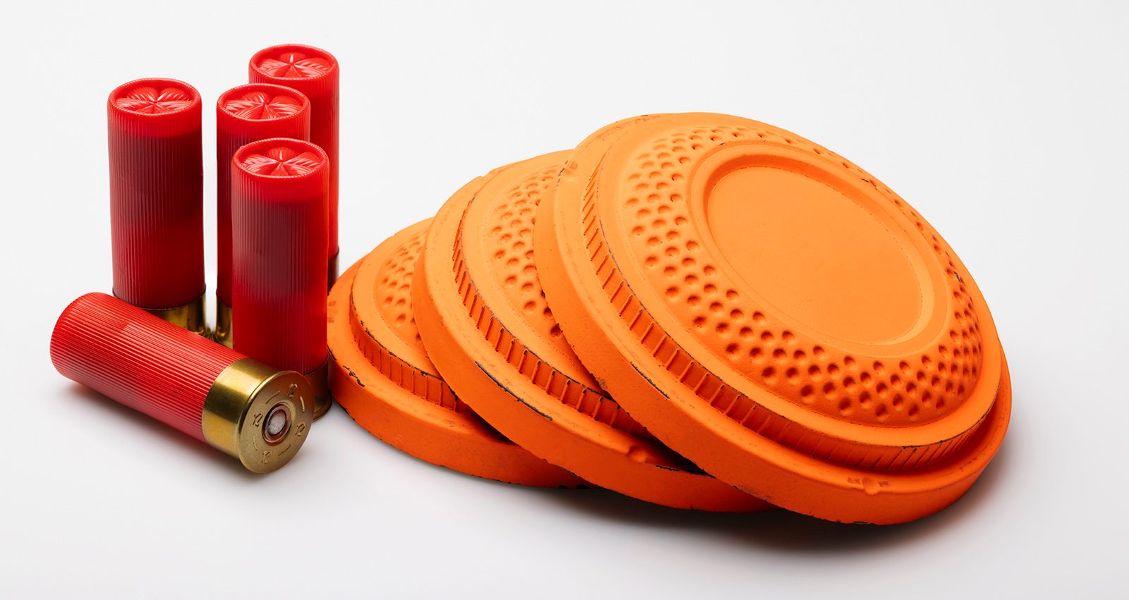Orange clay pigeons and red shotgun cartridges on a white background
