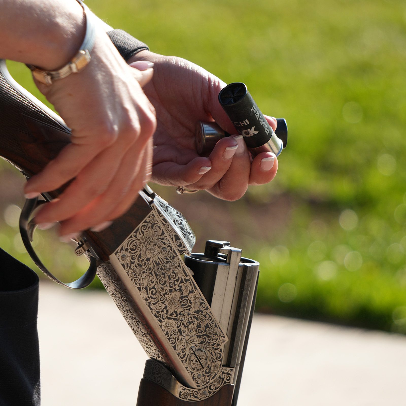A Fiocchi FBLACK game cartridge being loaded into an engraved side-by-side shotgun