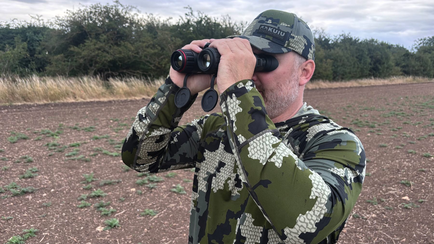 Danny Brookfield scanning an arable field edge with thermal binoculars on a summer evening