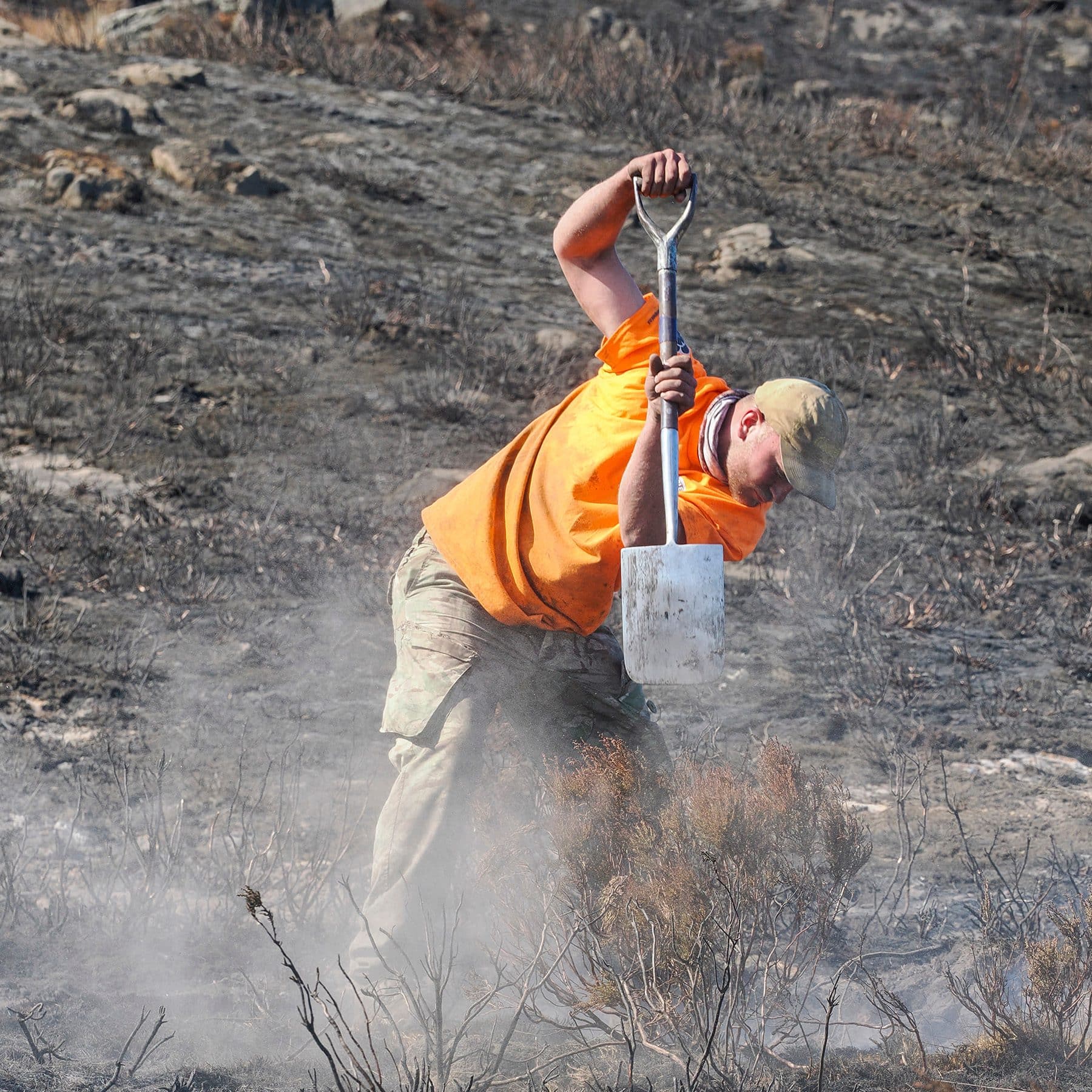 Gamekeeper digging out smouldering peat with a spade on burnt moorland in the Peak District