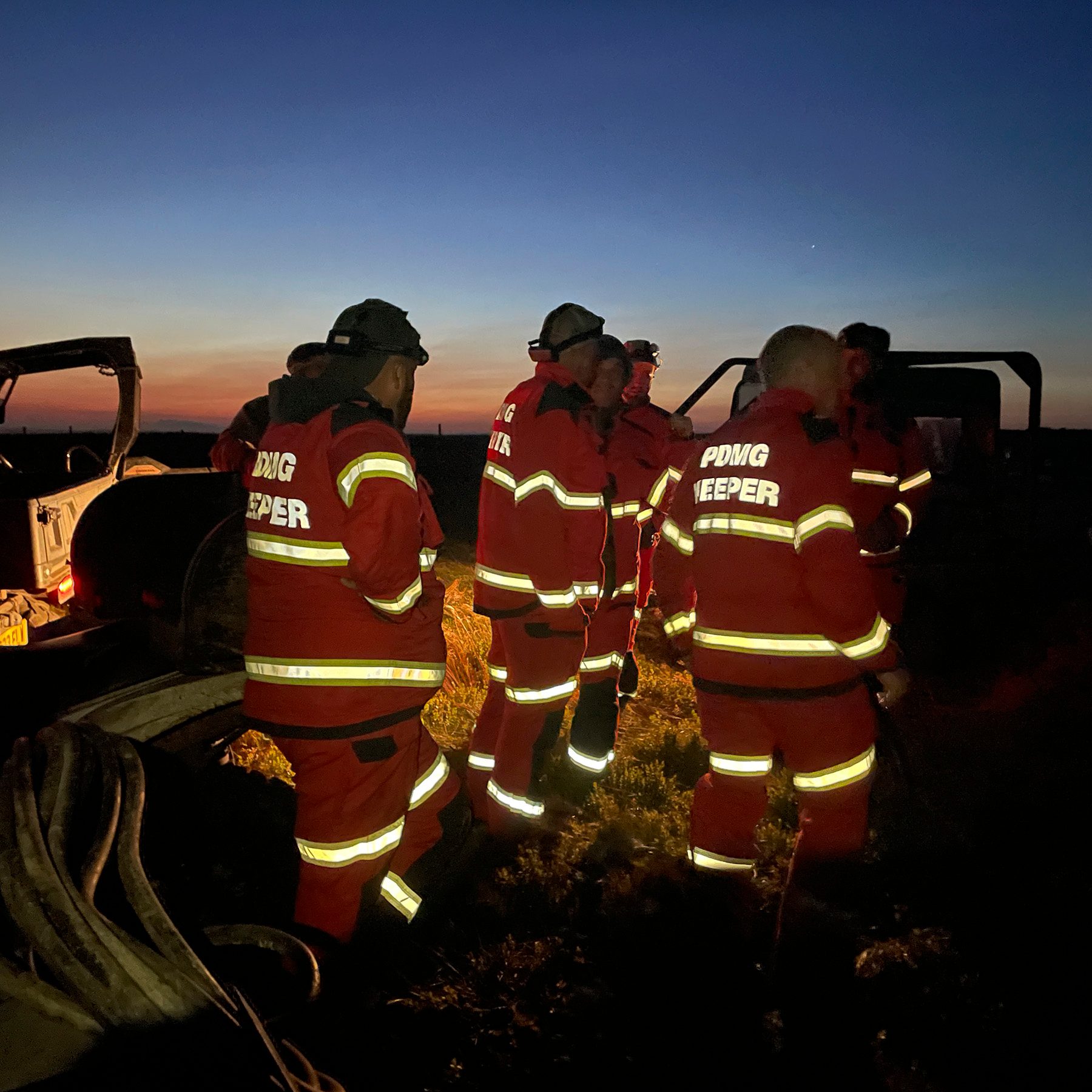 Gamekeepers at first light beside their vehicles during the Peak District wildfire night shift