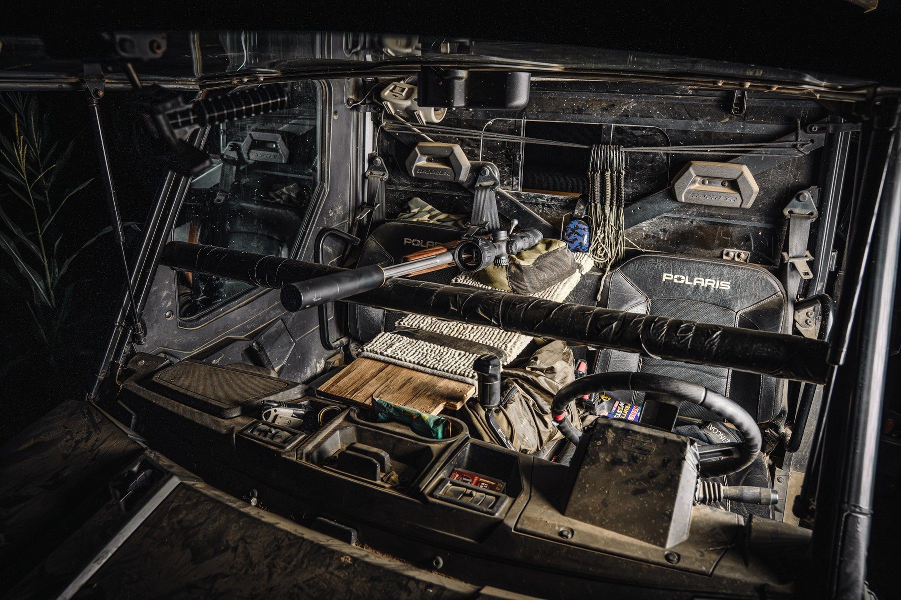 Inside the cab of a Polaris Ranger set up for night fox control, with a moderated rifle on a carpeted window rest