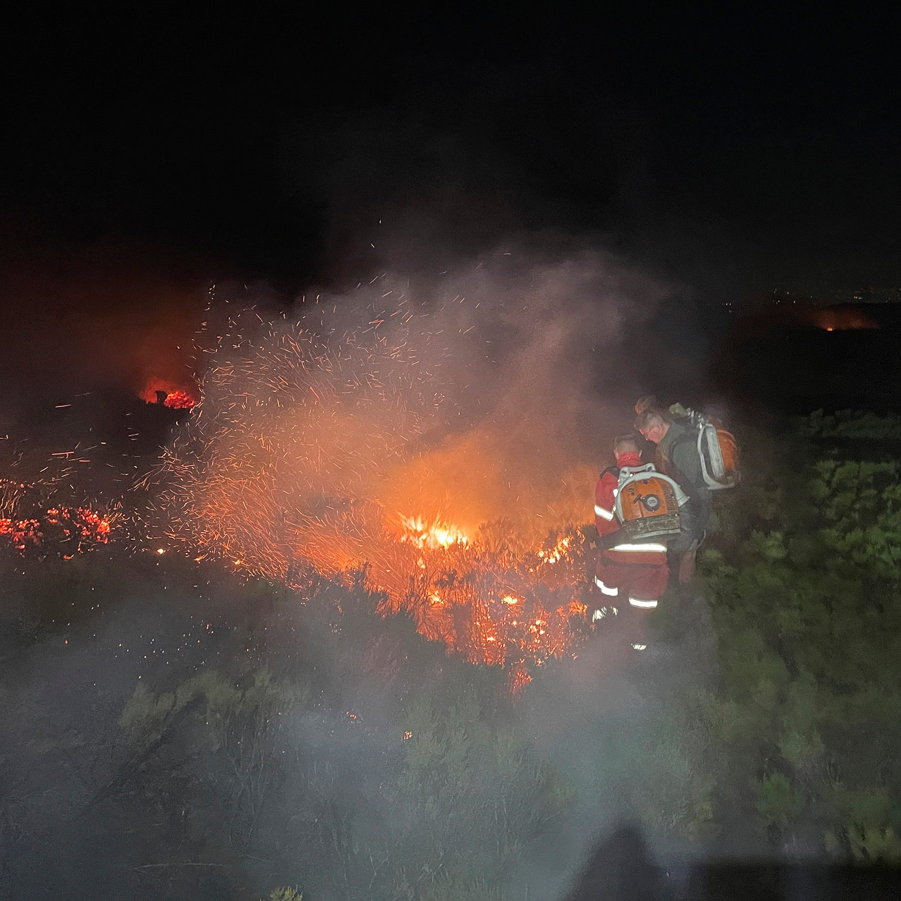 Flames burning across Tintwistle Moor at night as a gamekeeper works the fire front