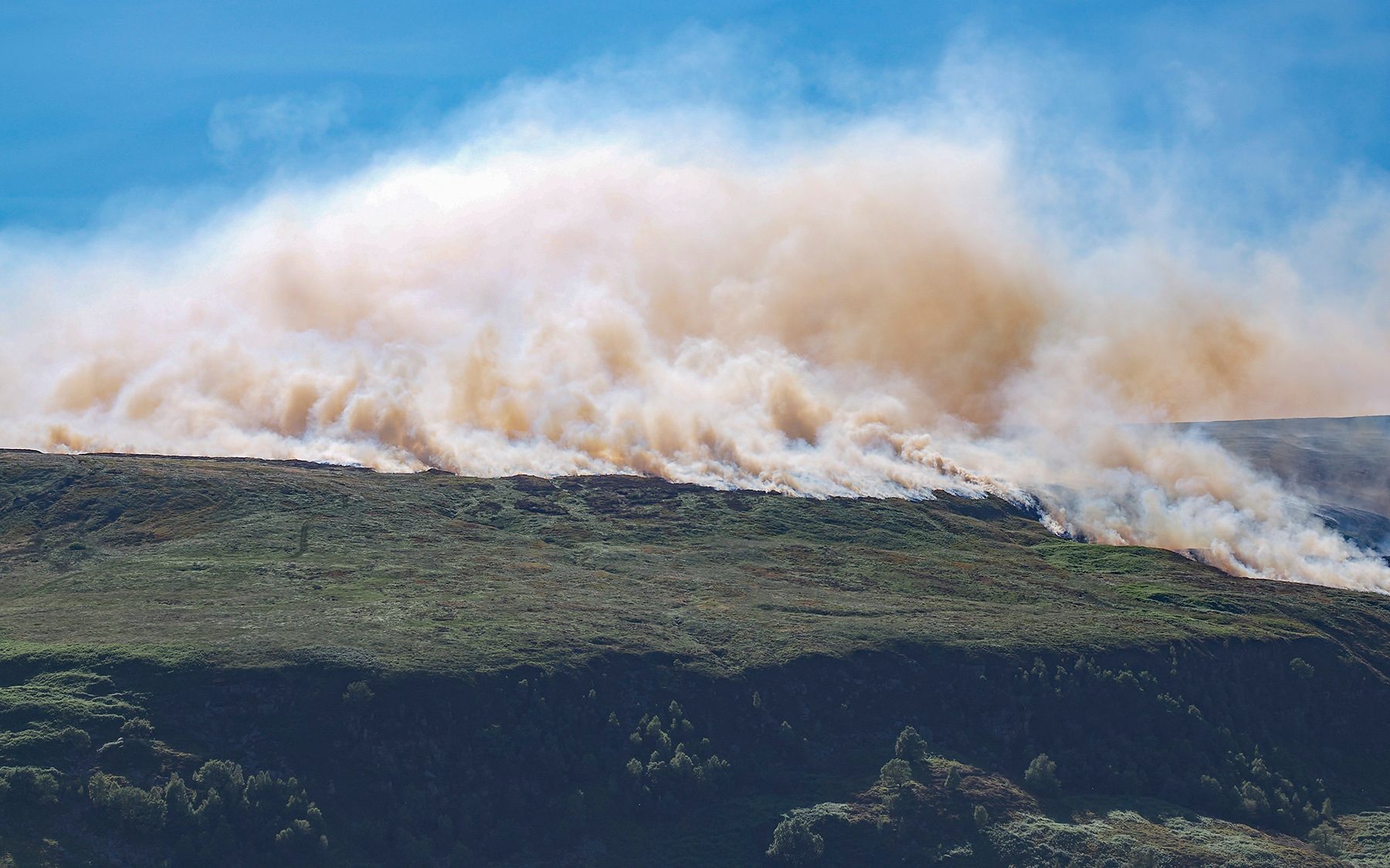 Wall of smoke rolling off burnt moorland during the Tintwistle Moor wildfire in the Peak District