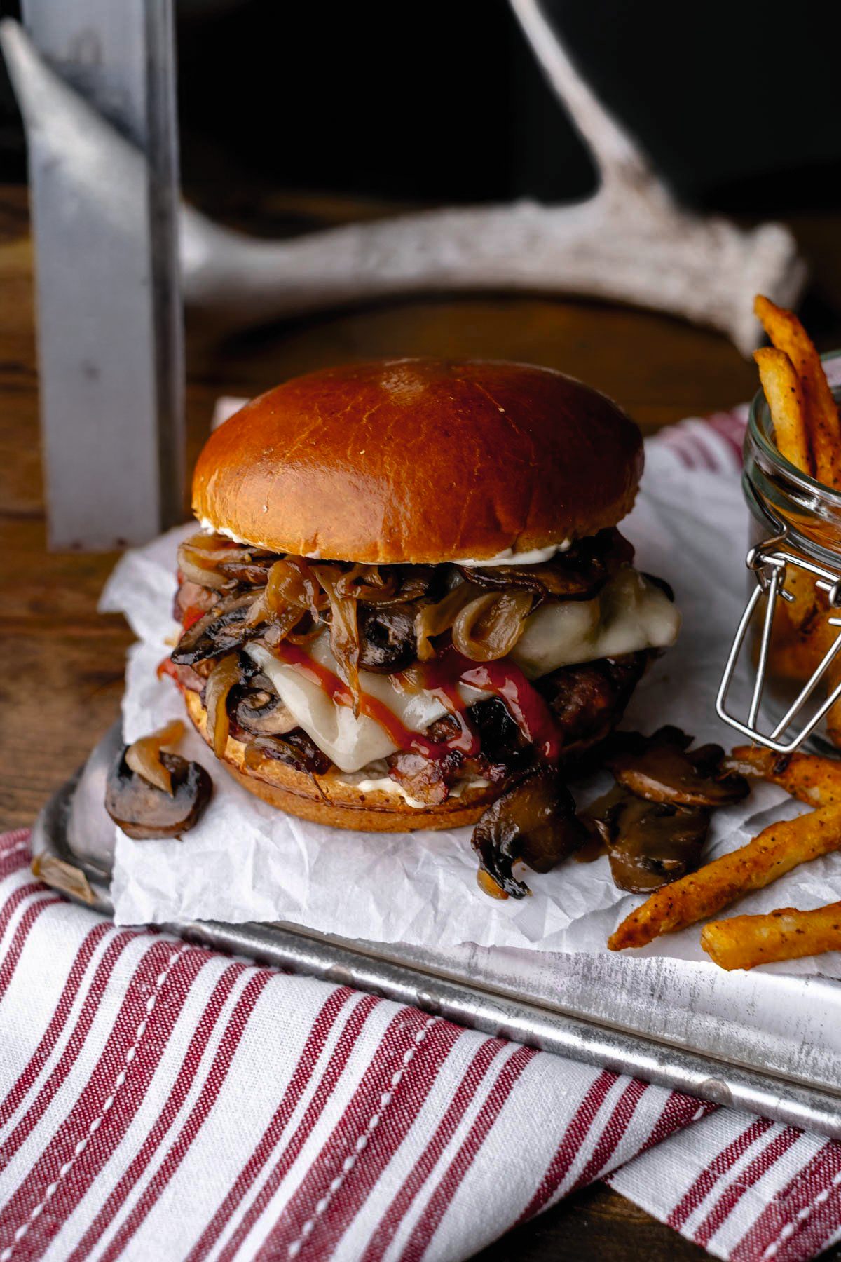 A venison burger in a toasted bun with melted cheese, lettuce and tomato