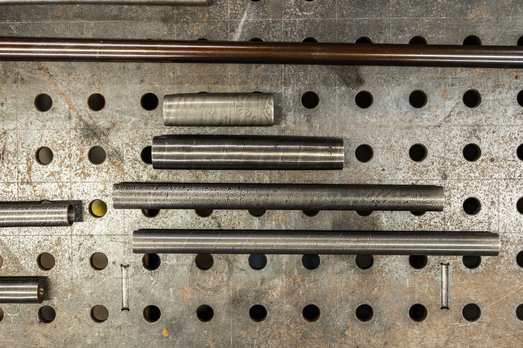 Forged damascus barrel tubes laid out on a swage block