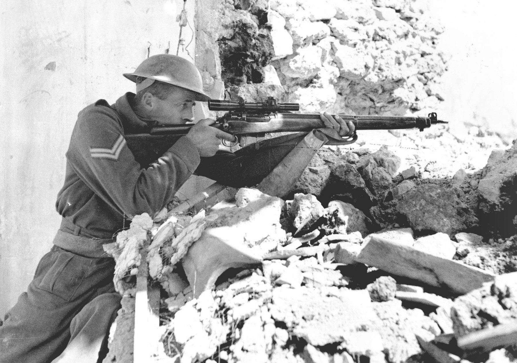 A New Zealand corporal aiming a scoped sniper rifle at Monte Cassino