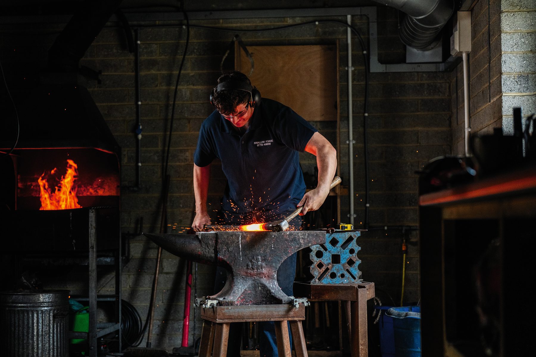 Sparks flying as Toby Smith hammers a barrel tube at the anvil