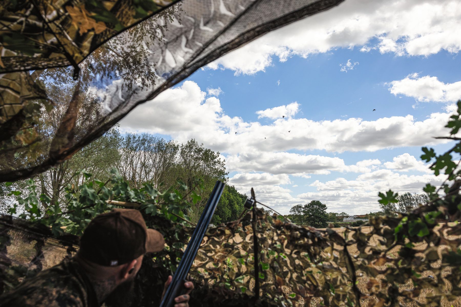 Two Guns concealed under a camouflage umbrella and nets in a hide beneath a willow